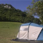 Tenda spaziosa montata su prato pianeggiante ai piedi di una parete rocciosa: natura e comfort nelle Piazzole per tende Abruzzo.