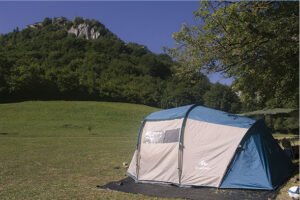 Tenda spaziosa montata su prato pianeggiante ai piedi di una parete rocciosa: natura e comfort nelle Piazzole per tende Abruzzo.