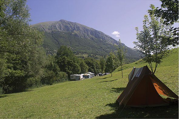 Tenda e roulotte su prato verde ai piedi del Monte Marsicano: vacanza autentica nelle Piazzole per tende Abruzzo.