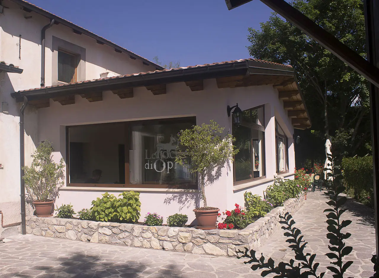 Ingresso fiorito del ristorante Le Foci di Opi, con ampie vetrate e atmosfera accogliente: gusto e relax al Ristorante campeggio Abruzzo.